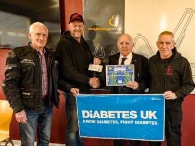 The image shows four mean holding a Diabetes UK banner.