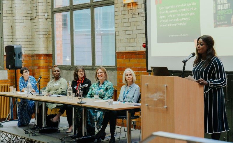 Members of the Tackling Inequality commission sit on a panel listening to a speech