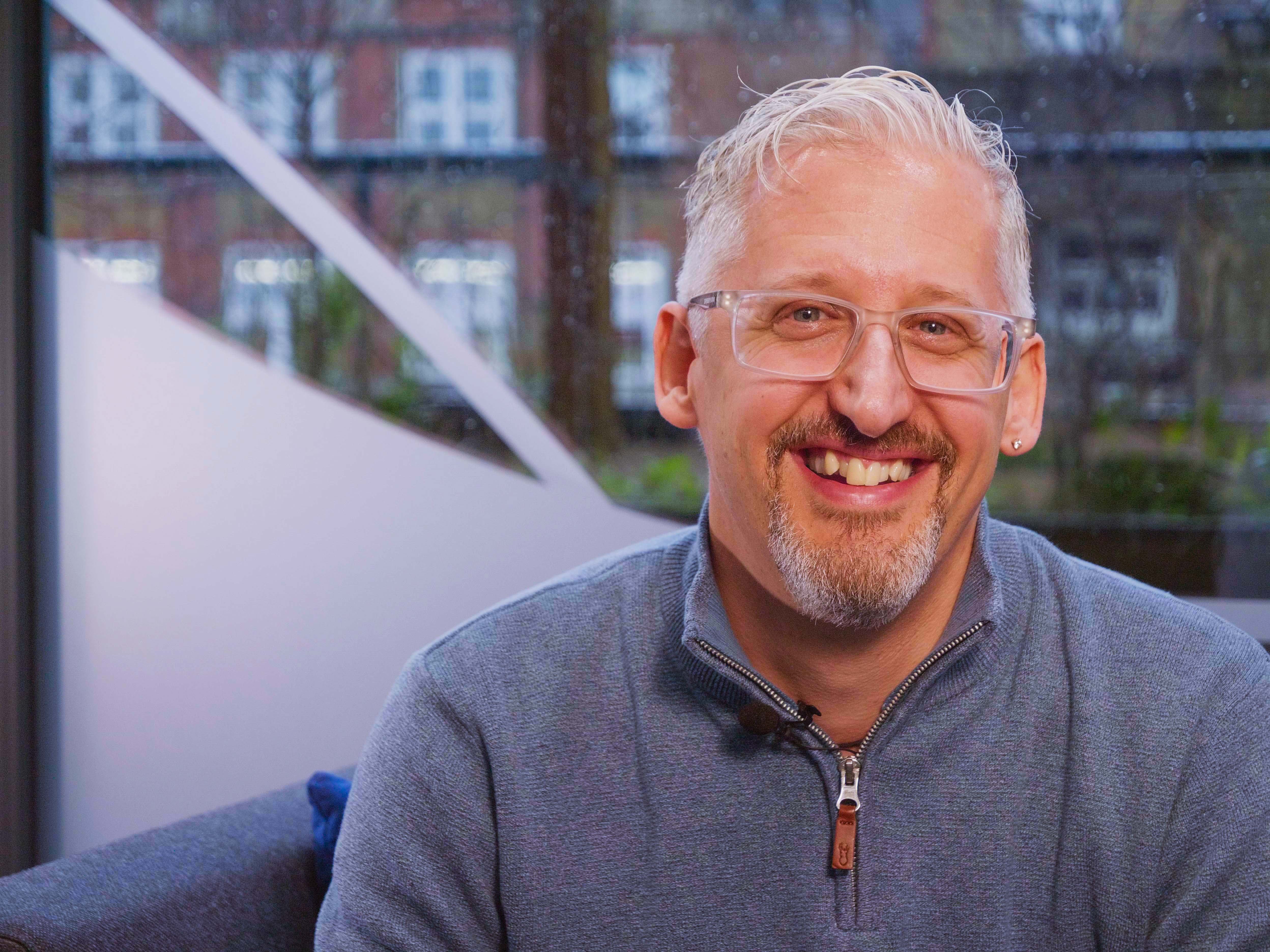 Man with grey and a beard smiles broadly at the camera