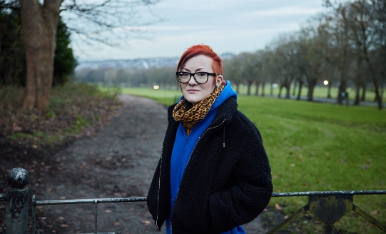 Woman looking at the camera standing in front of a field