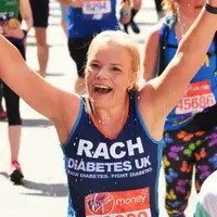 Female Runner in Diabetes UK running vest with arms raised.