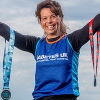 Lucy in Diabetes UK running vest holding medals.