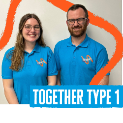 Sam and Sian wear blue Together Type 1 polo shirts and stand next to each other in front of a white wall, smiling at the camera.