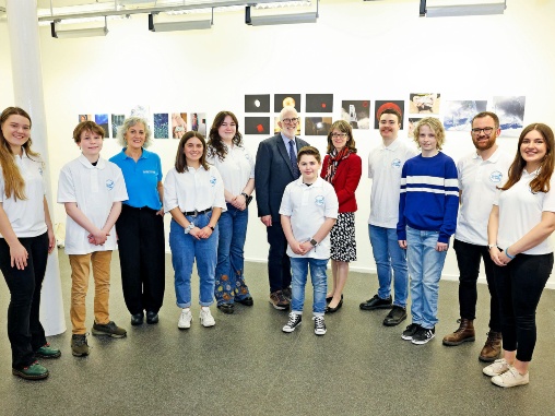 A group of young people stand in a semi-circle smiling at the camera. They are joined by Diabetes UK staff members including the CEO in the centre of the picture.