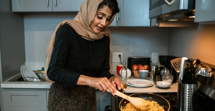 A woman cooks in a pan in her kitchen