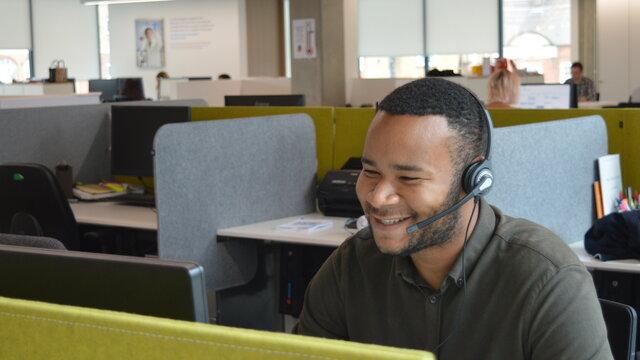 A Diabetes UK Helpline Advisor smiling as he chats to a supporter over the phone