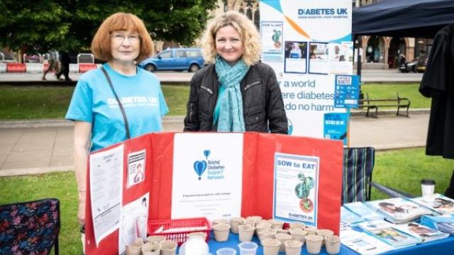 Two women volunteering at an advice table at an outdoors event