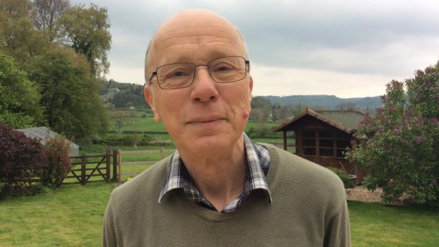 A photo of David outside with a field in the background