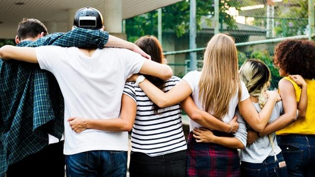 A group of teenagers stand with their arms around each other