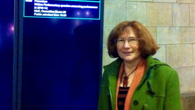 A woman wearing a green coat is smiling at the camera