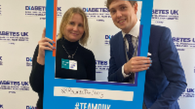 The image shows a women and a man holding a Diabetes UK blue selfie frame. 