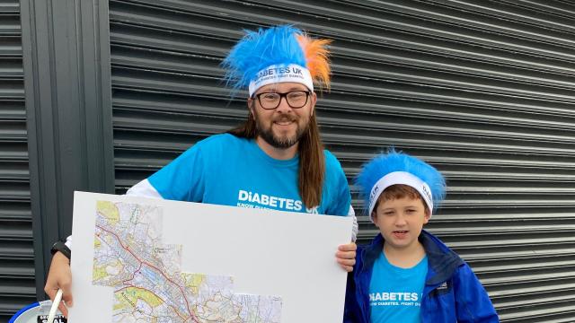 A man and his son wearing Diabetes UK tshirts and 'crazy hair' holding a map