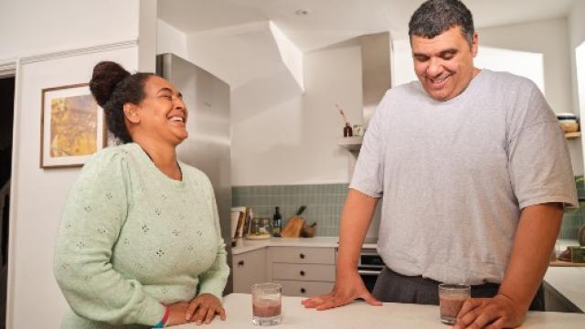 A woman and a man stand at a kitchen counter smiling 