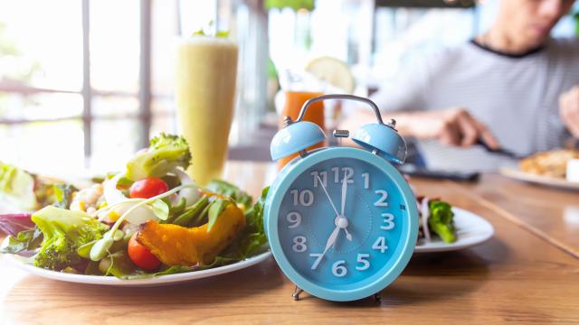 An alarm clock next to a plate of salad