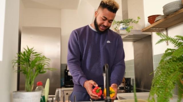 Man washes peppers at a sink