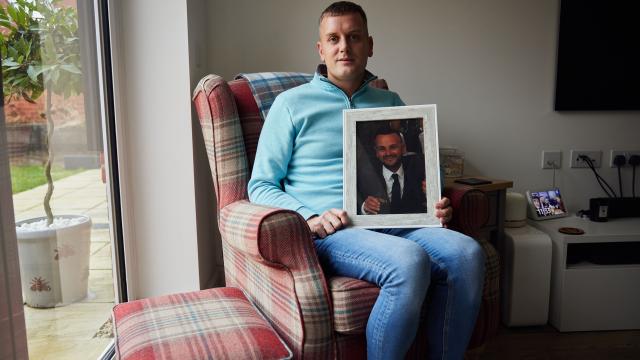 Man sitting down and holding a framed photograph