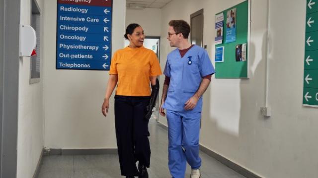 A healthcare professional walking with a patient in a corridor