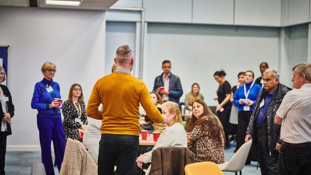 A group of people at an event listening to a talk