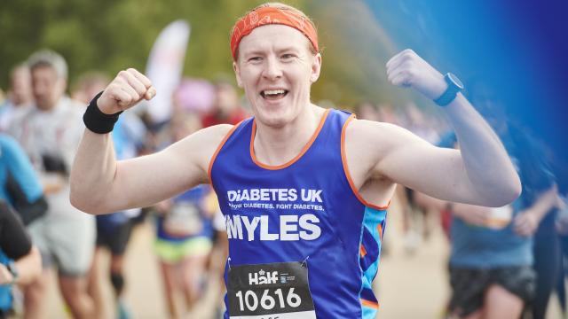 Male runner fists in the air in Diabetes UK running vest looking triumphant.