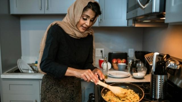 A woman cooking in a pan in her kitchen.