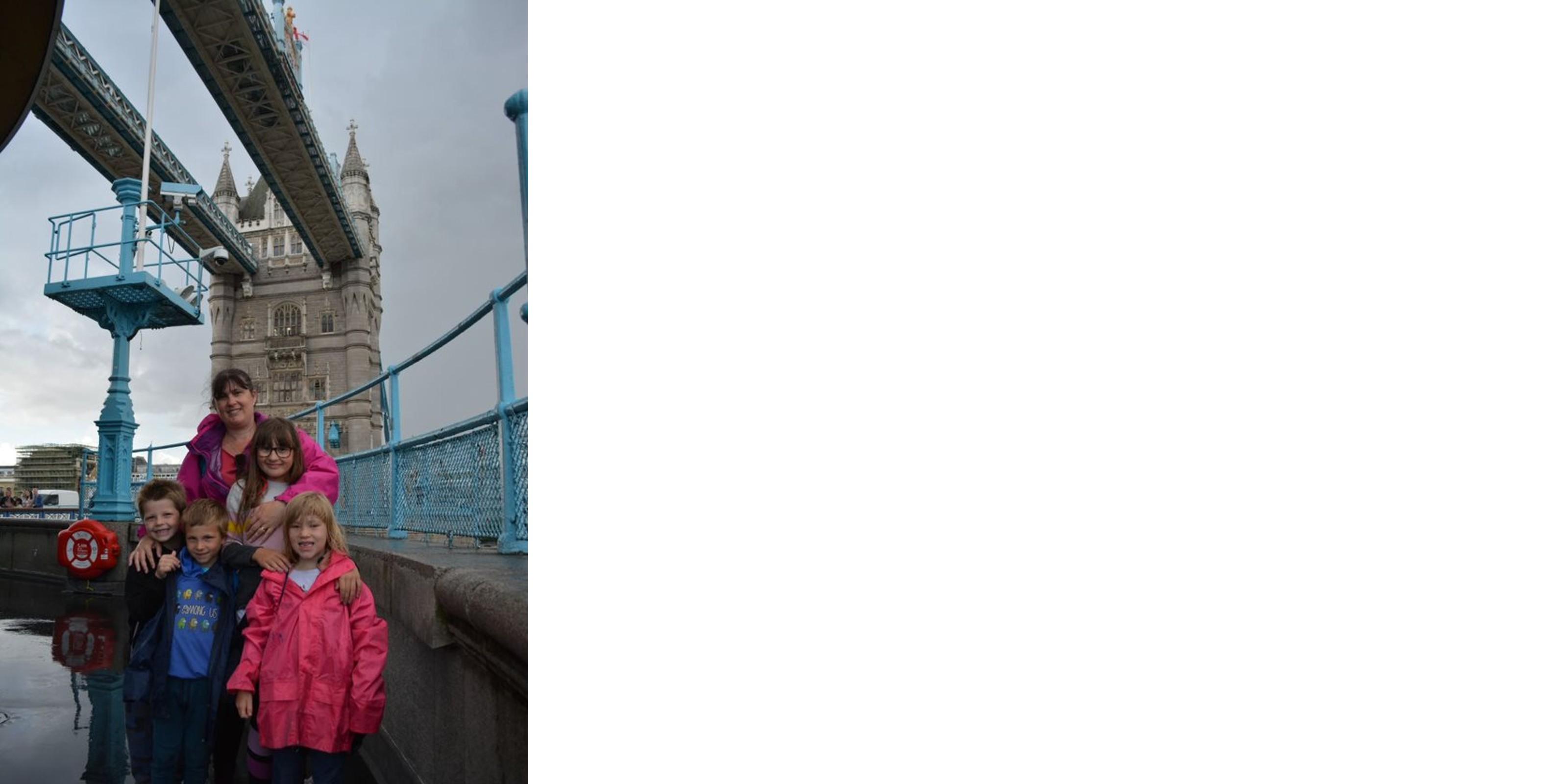 Amanda and her 4 children stand in front of London's Tower bridge whilst smiling at the camera