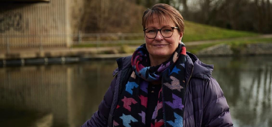 Lady stands by a canal smiling into the camera