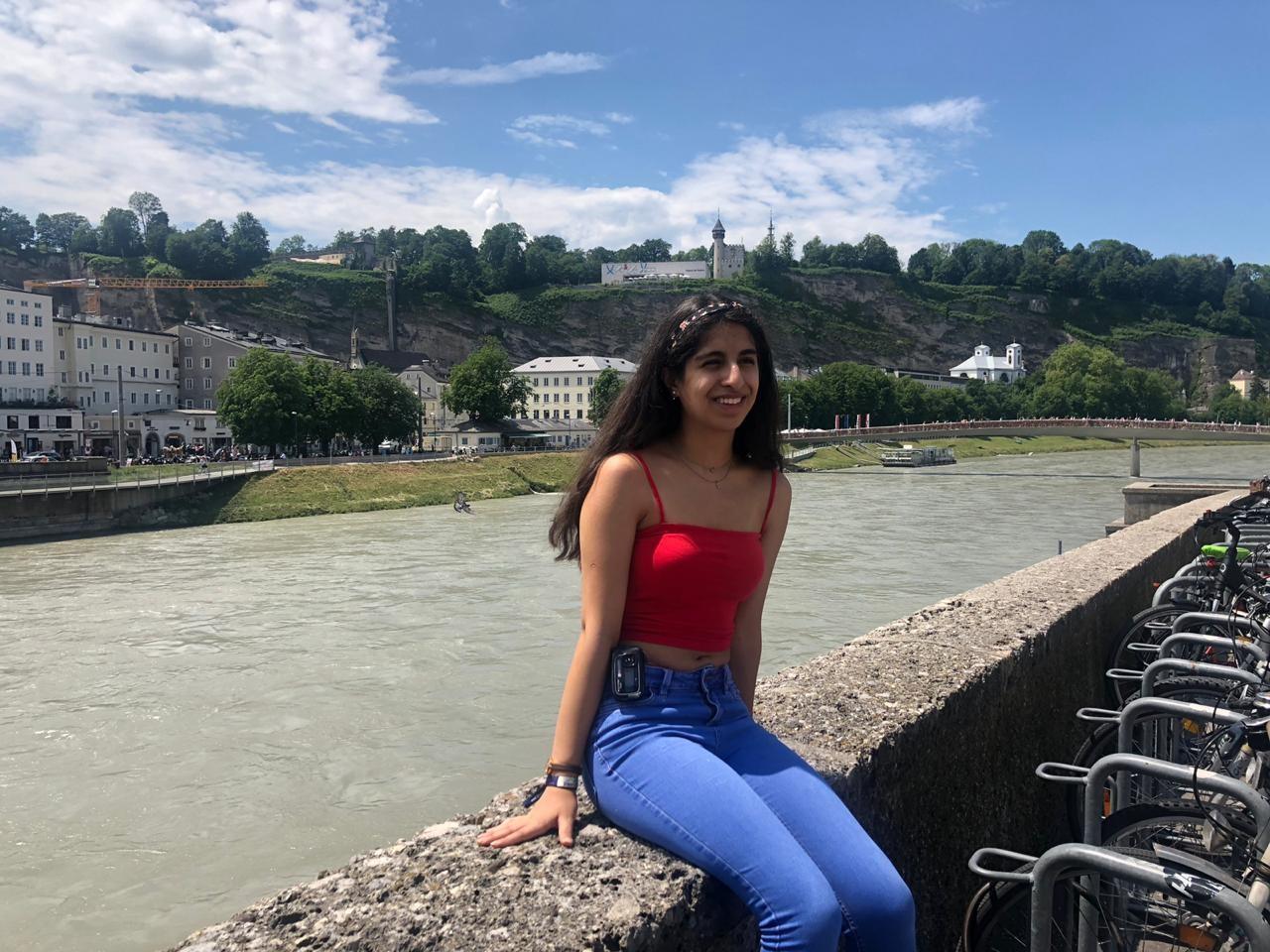 A young woman is sitting by a river