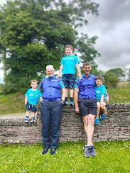 The McStravock family sitting on a wall with trees in the background