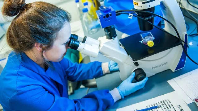 Women scientist looking down microscope