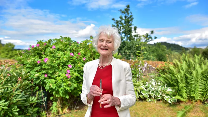 Dr Sheila Reith standing in her garden, holding her insulin pen prototype