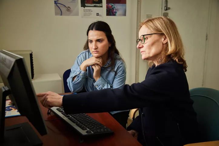 A GP sitting at a computer with a patient