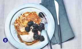 Pancakes with yoghurt and berries on a plate with a knife next to it