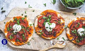 Three harissa tomato tarts on a wooden chopping board