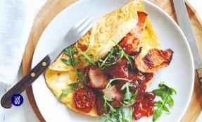 A sausage bacon omelette next to some salad on a plate