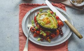 Eggs and avocado on plate with knife and fork