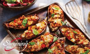 Stuffed baked aubergines on an oven pan with a spatula to the left