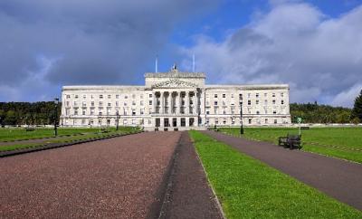 A photograph of the front of Stormont, Northern Ireland's parliament building, a large white building with green lawn on either side