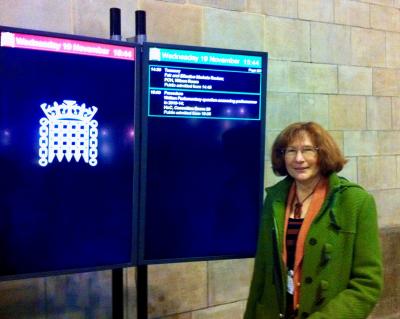 A woman wearing a green coat is standing next to a screen