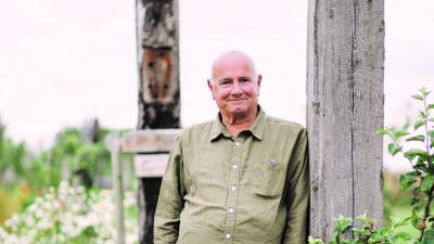 A man in a green shirt is leaning against a wooden post